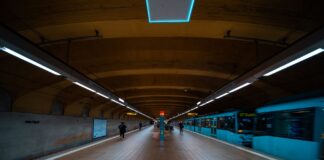 Jak poruszać się po krajach Zatoki: metro w Dubaju, taksówki, wynajem auta i zasady Pasażerowie na peronie metra w Dubaju obok jadącego niebieskiego pociągu