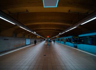 Pasażerowie na peronie metra w Dubaju obok jadącego niebieskiego pociągu