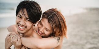 Tani miesiąc miodowy w Azji: romantyczne, a jednocześnie budżetowe kierunki dla par Wytatuowana para przytula się i uśmiecha na piaszczystej azjatyckiej plaży