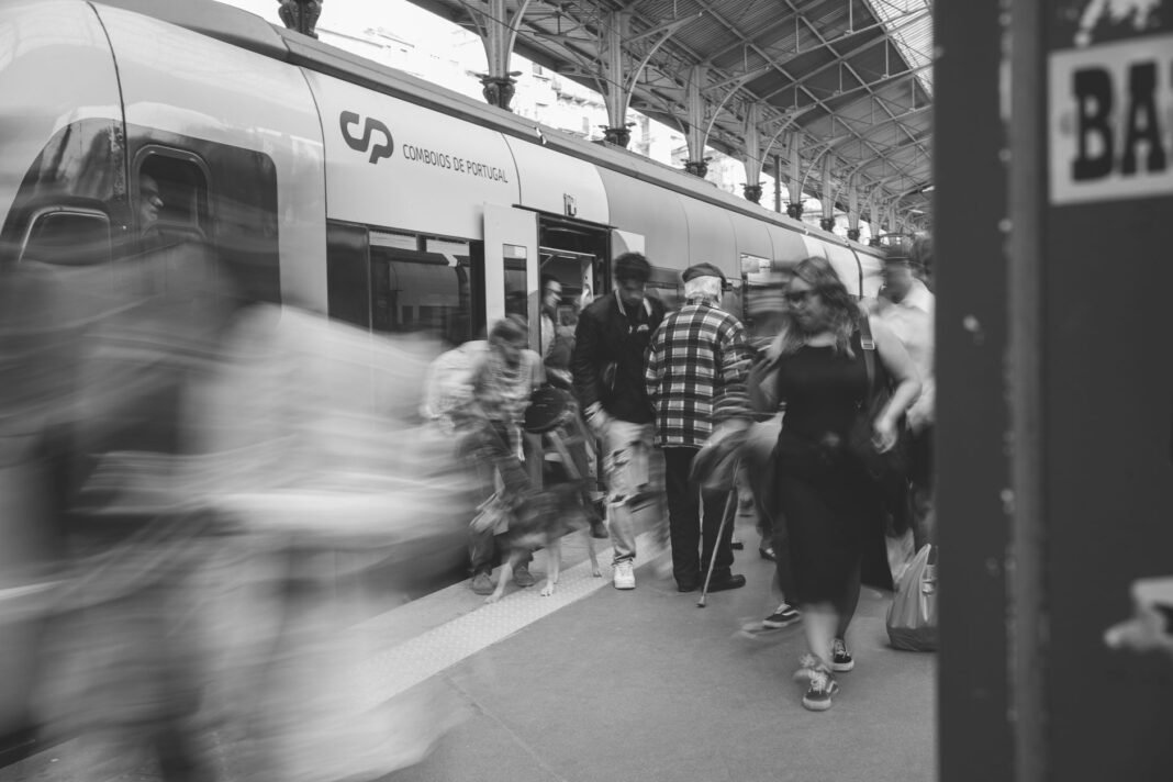 Dojazdowi pasażerowie na dworcu kolejowym w Lizbonie w czerni i bieli