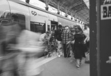 Jak tanio poruszać się po Europie pociągiem: praktyczny przewodnik Dojazdowi pasażerowie na dworcu kolejowym w Lizbonie w czerni i bieli