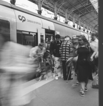 Dojazdowi pasażerowie na dworcu kolejowym w Lizbonie w czerni i bieli
