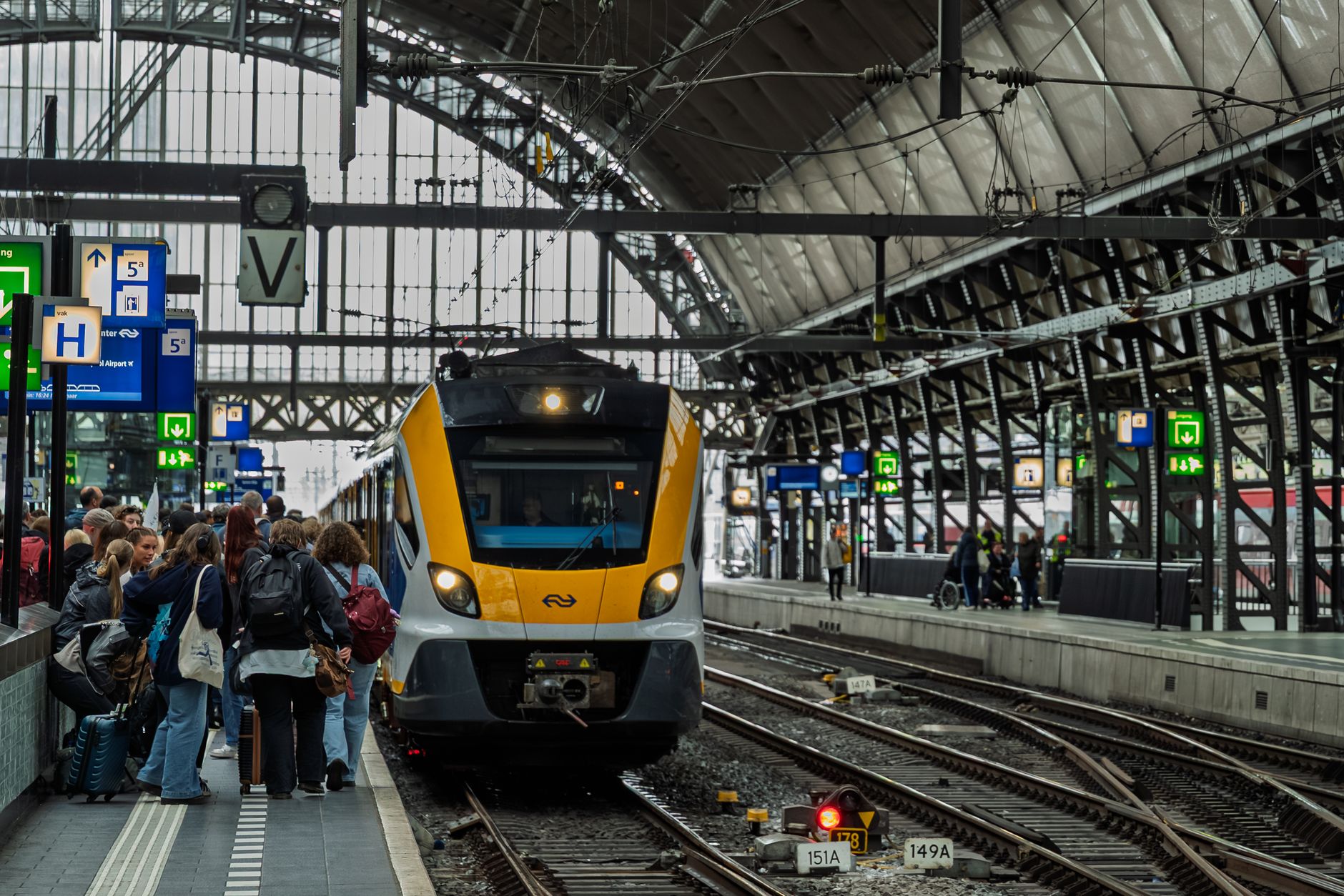 Tłoczny peron na dworcu Amsterdam Central i nadjeżdżający pociąg