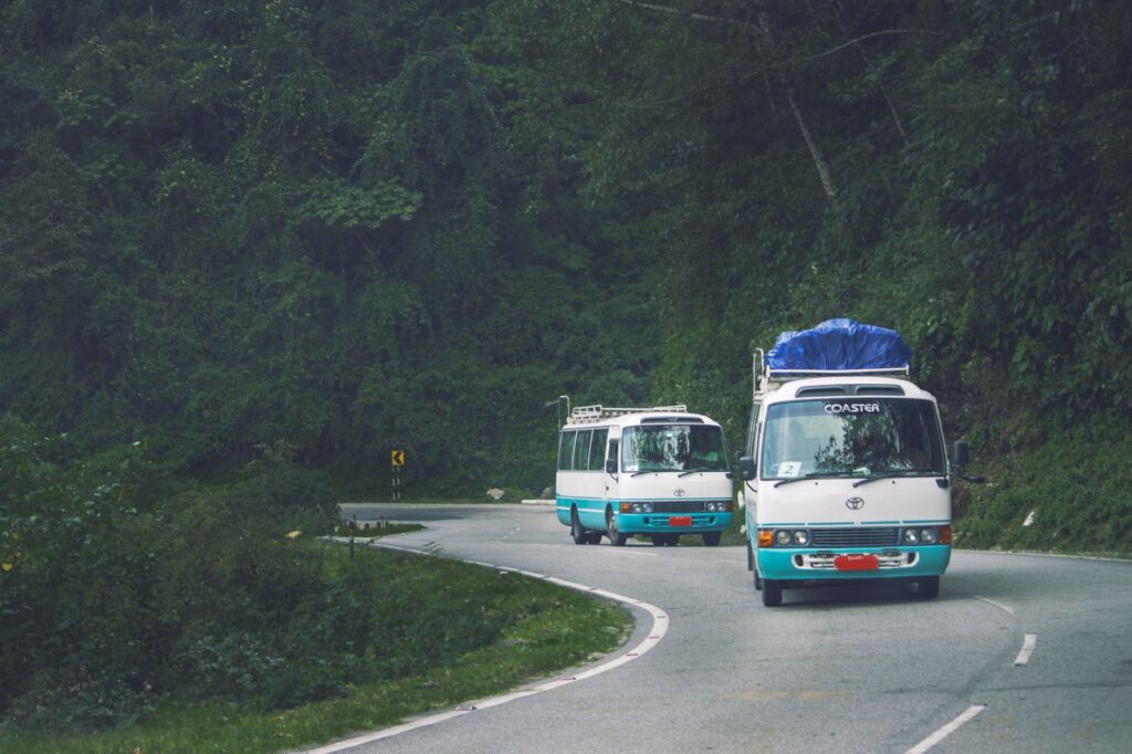 Dwa minibusy na górskiej drodze wśród zielonych lasów Bhutanu